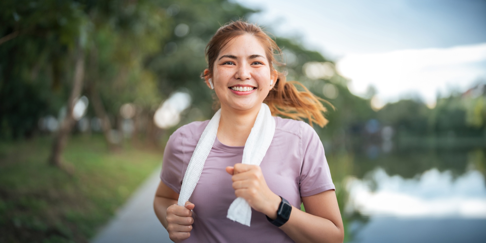 Young smiling sporty woman running in park in the morning. Fitness girl jogging in park